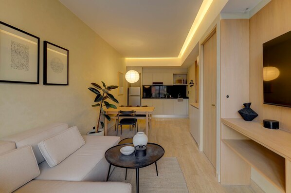 A modern living room with a sofa, a coffee table, and a dining area with a table and chairs. - Aristoteles Elegance Comfort 1 BR Apartment wit (Mexico City)