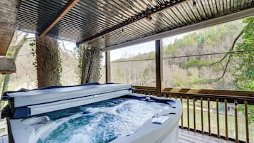 Un bain à remous avec une terrasse en bois et vue sur une forêt.