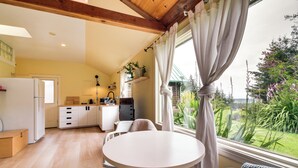 Una cocina compacta con zona de comedor, un refrigerador y una ventana con cortinas.