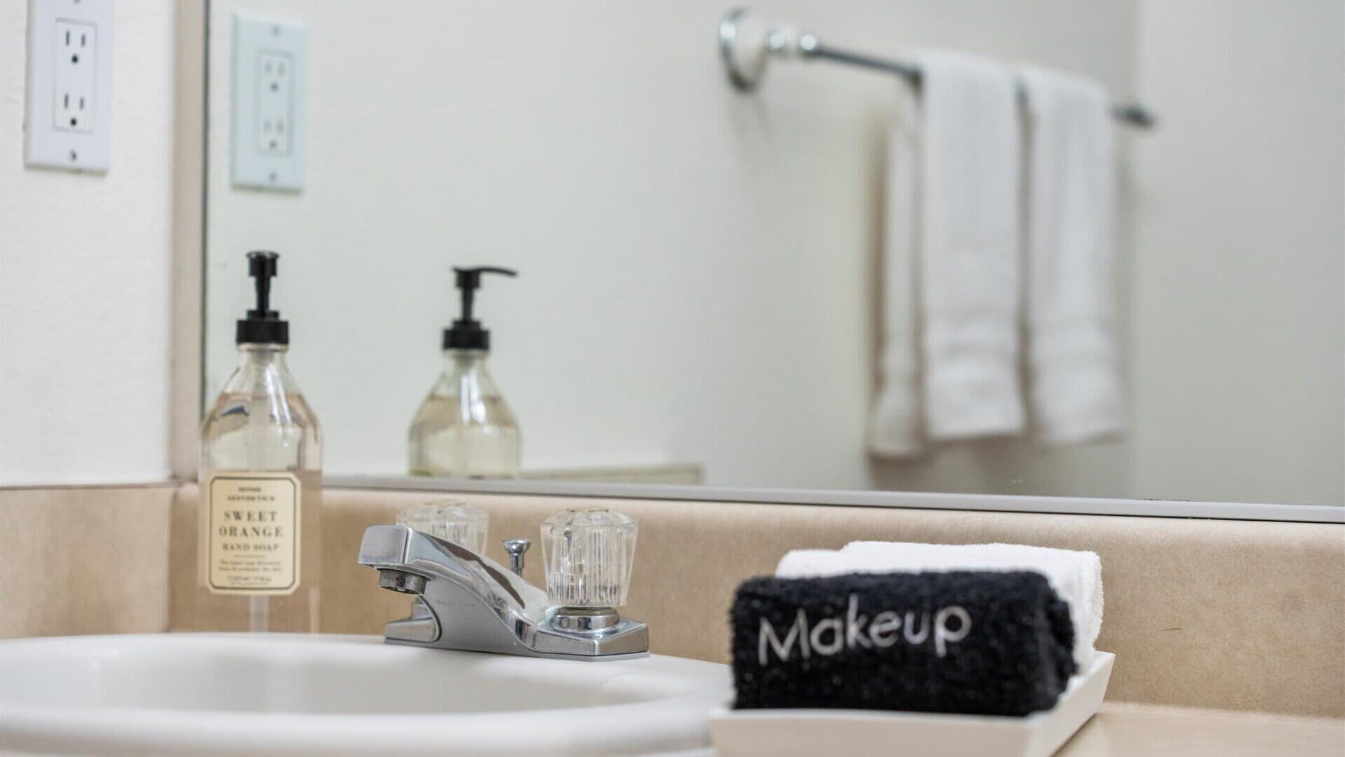 A bathroom with a sink, a mirror, and a towel rack.