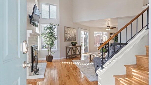 Un salon spacieux doté de planchers en bois, d’une cheminée, d’une grande plante en pot et d’un escalier avec des rampes en bois.