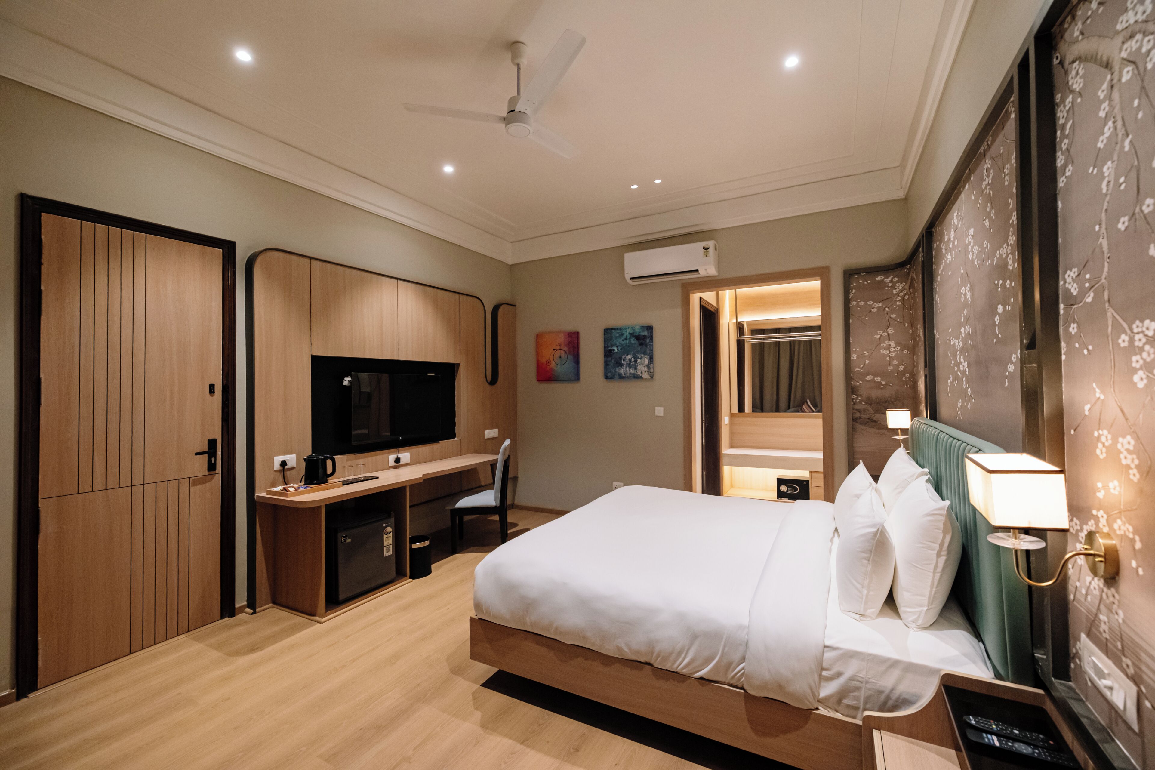 A hotel room with a bed, desk, TV, and a ceiling fan.