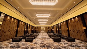 A hotel lobby with a long row of seating, a chandelier, and a patterned wall design. - Pride Premier Alwar, Sariska  (Alwar)