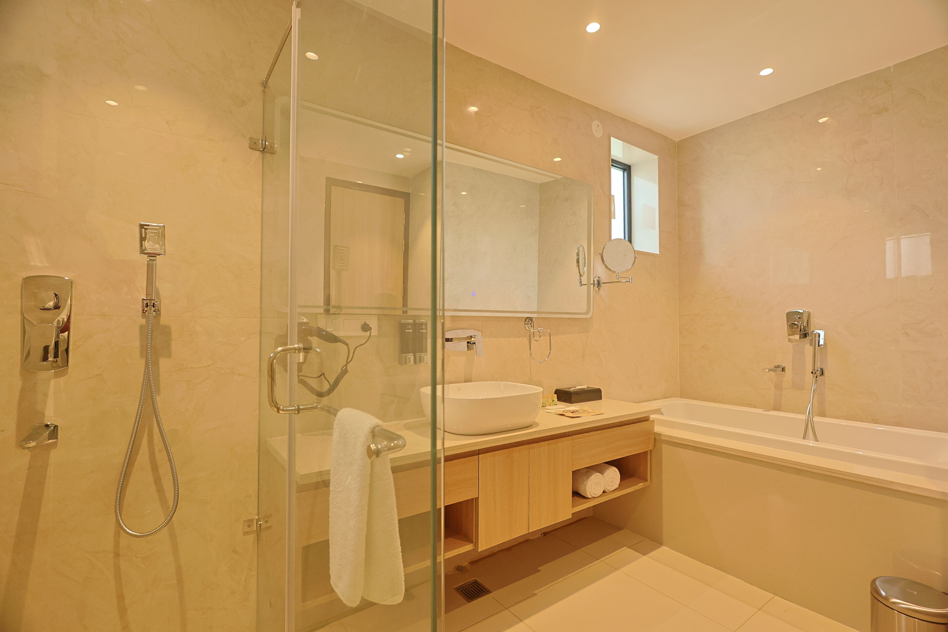 Une salle de bain moderne avec une douche à parois de verre, un grand miroir, une baignoire et un meuble-lavabo.
