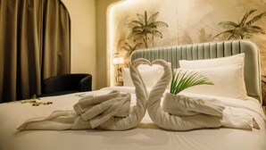 A hotel room with a bed, a plant, and a wall with palm tree murals. - Pride Premier Alwar, Sariska  (Alwar)