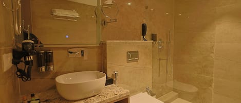 Un baño moderno con un lavabo grande, un inodoro, una ducha y un espejo.