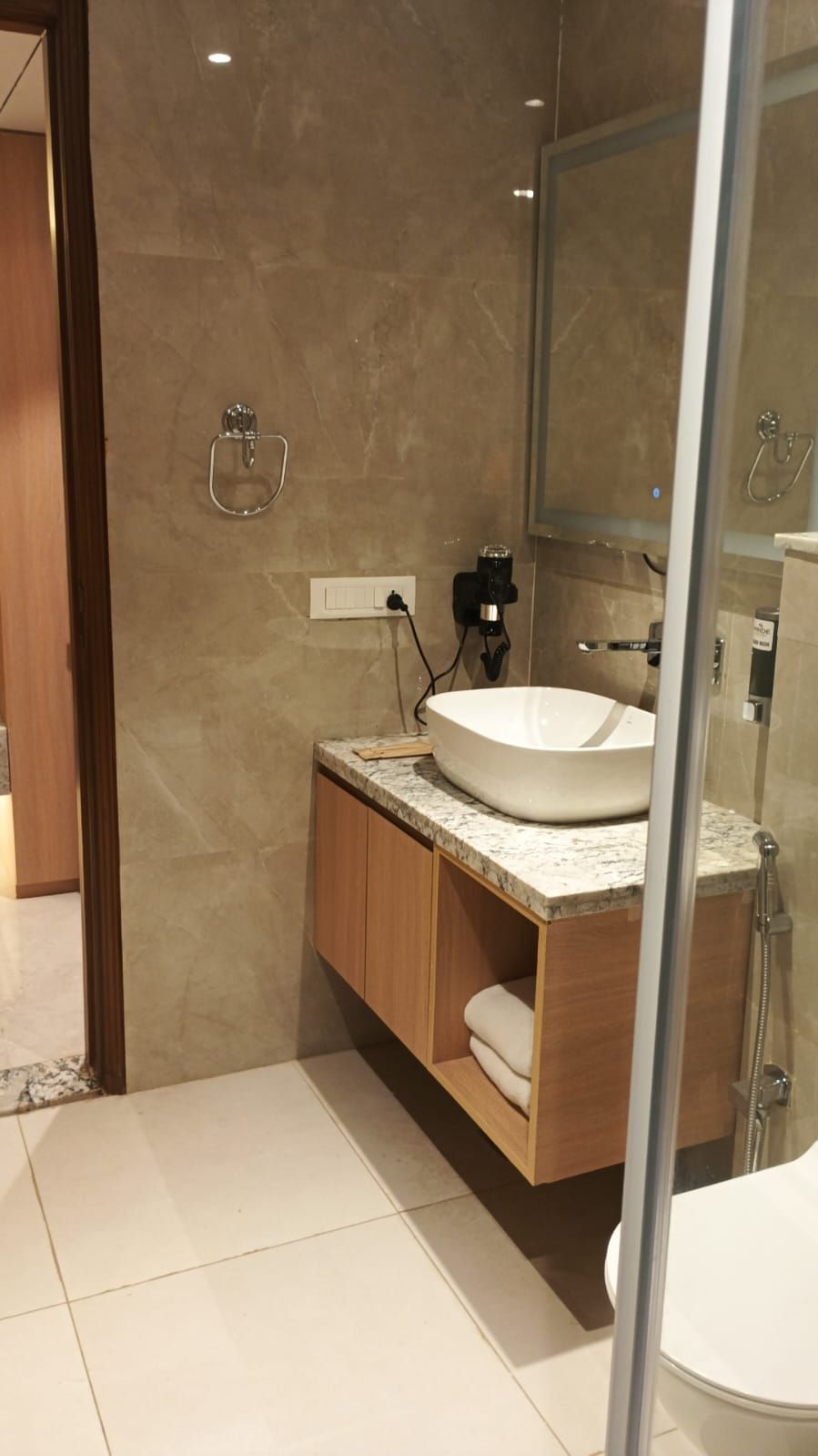 A modern bathroom with a large sink, wooden cabinets, a glass shower enclosure, and a mirror.