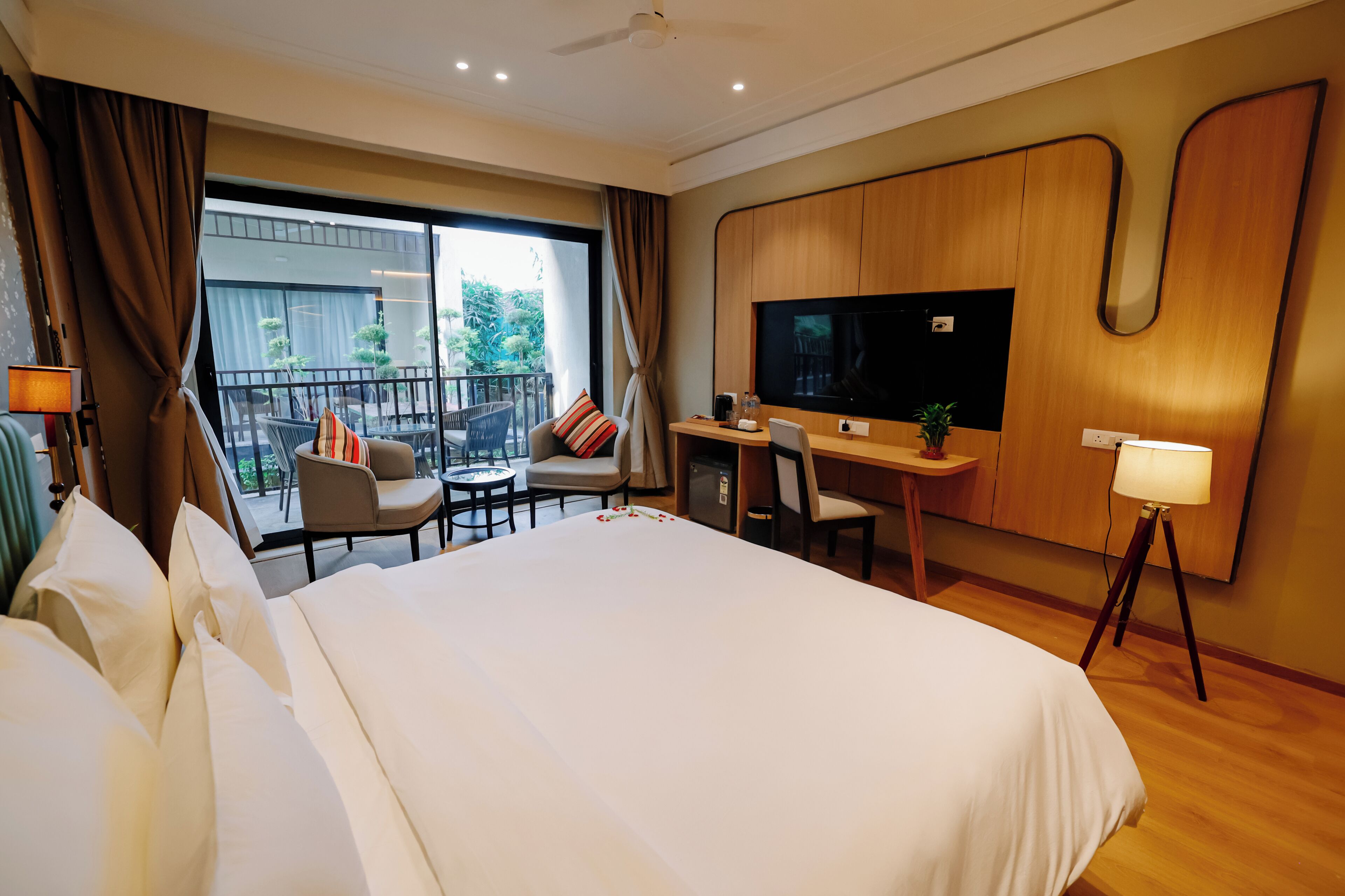 Une chambre d’hôtel dotée d’un grand lit, d’un bureau avec une chaise, d’une télévision et d’un balcon aménagé avec du mobilier d’extérieur.