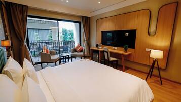 Une chambre d’hôtel dotée d’un grand lit, d’un bureau avec une chaise, d’une télévision et d’un balcon aménagé avec du mobilier d’extérieur.