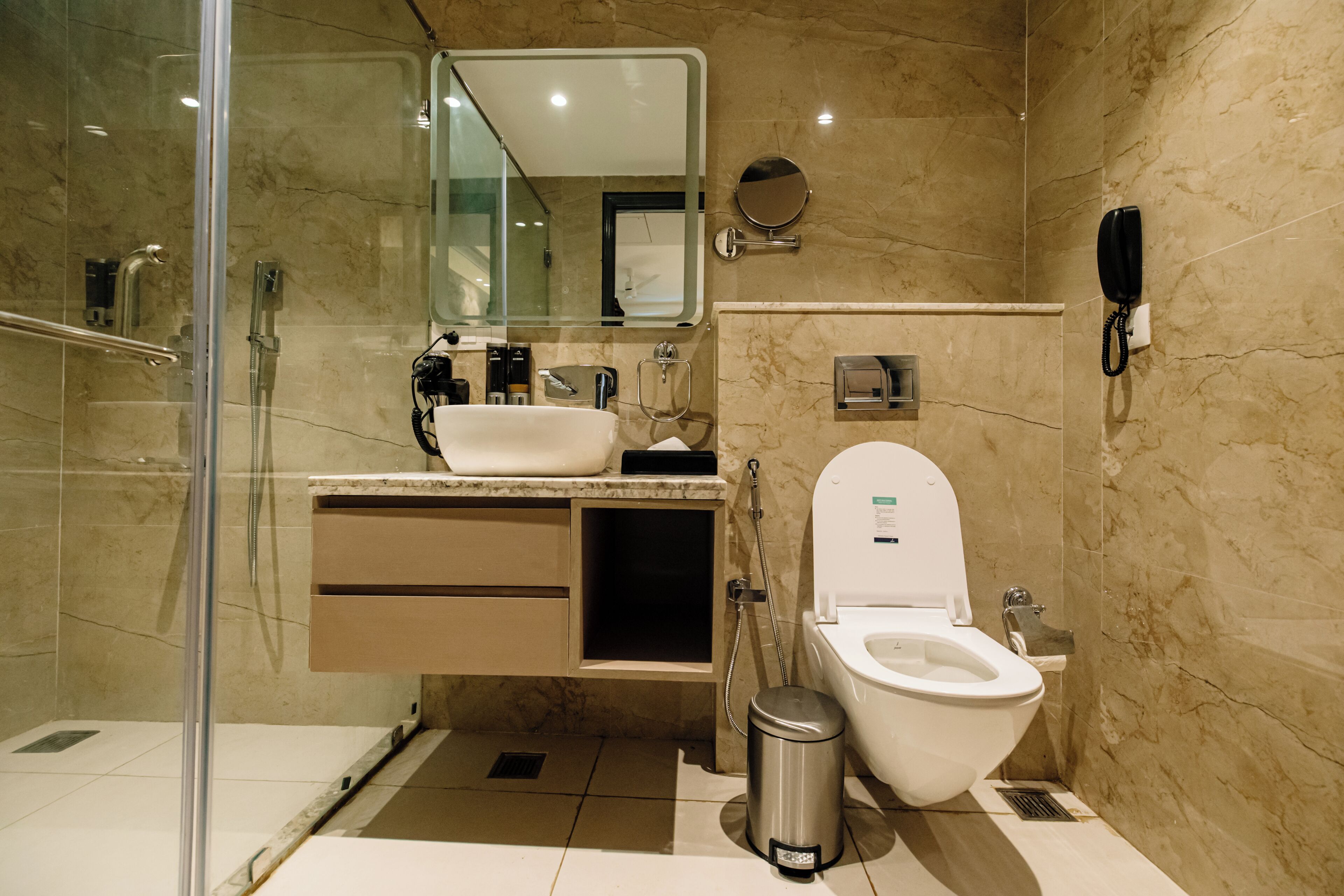 Un baño moderno con cabina de ducha de vidrio, inodoro, lavabo y espejo.