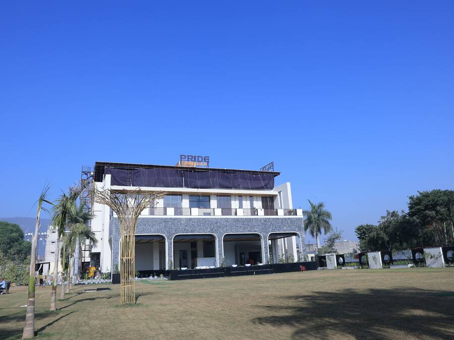 A modern building with a covered entrance, a sign reading 'PRIDE,' and a grassy area in front.