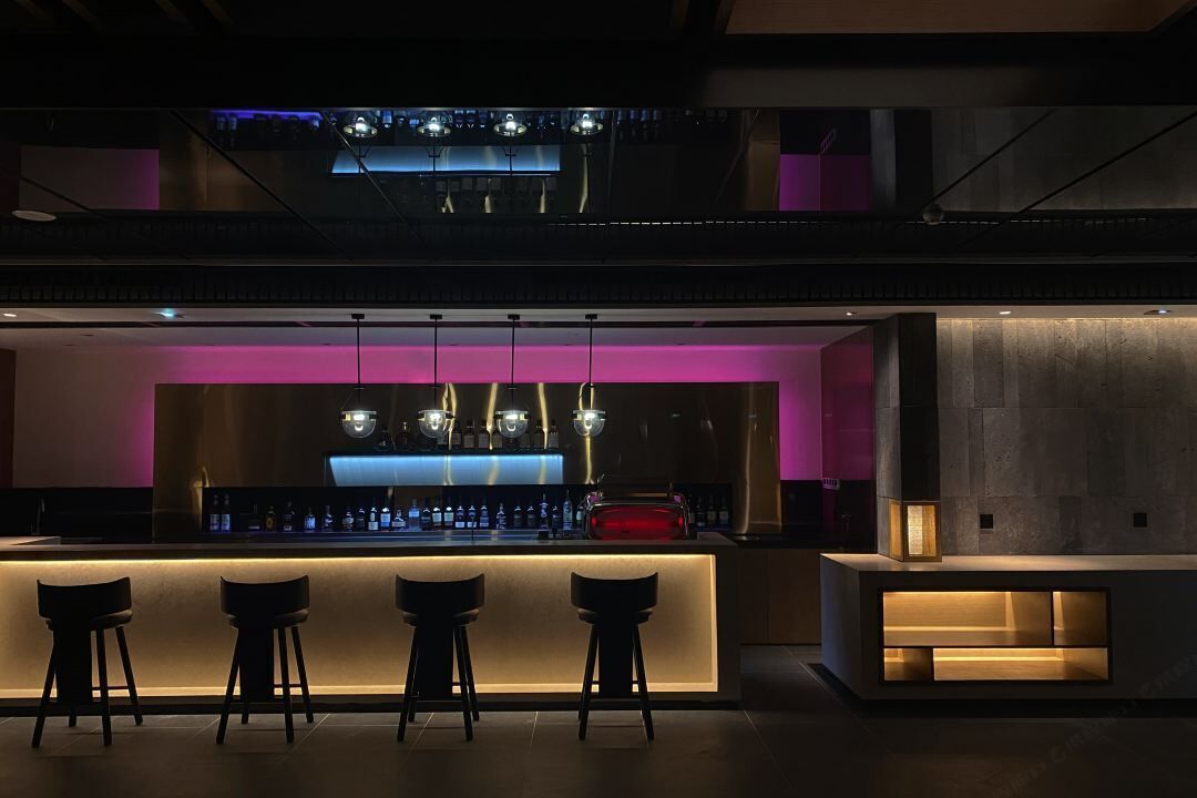 A modern bar area with a counter, bar stools, and pendant lighting.