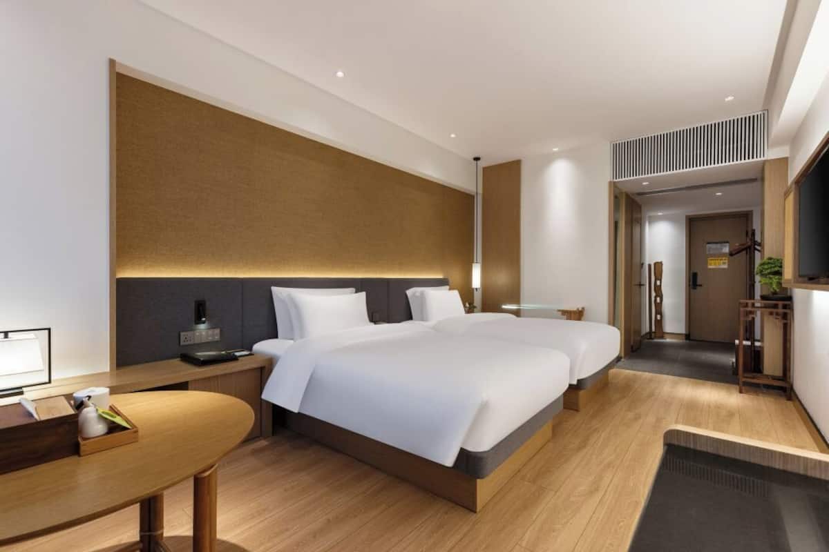 Una habitación de hotel moderna con una cama grande, mesitas de noche, un escritorio y un televisor.