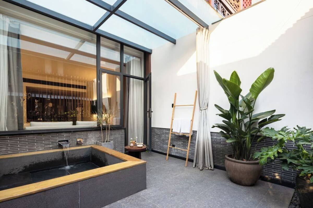 Un baño moderno con una bañera independiente, una ventana con cortinas y una planta en maceta.