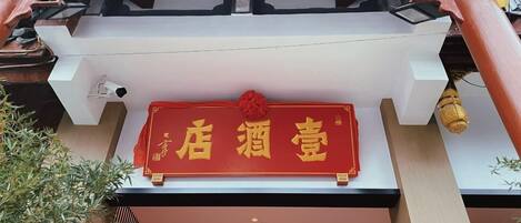 Een rood bord met gouden Chinese karakters op de gevel van een gebouw.
