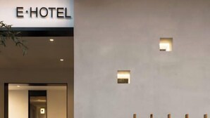 A modern hotel entrance with a minimalist design, featuring a signboard, a wooden fence, and a small table. - E Hotel-Kuanzhai Alley (Chengdu)