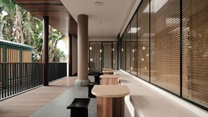 A corridor with wooden tables and benches, large windows with blinds, and a view of greenery outside. - E Hotel-Kuanzhai Alley (Chengdu)