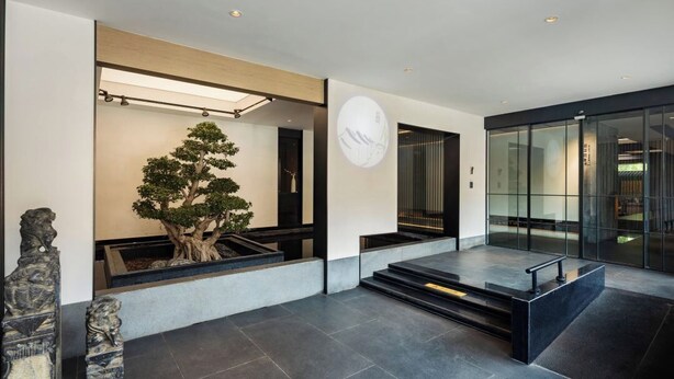 A modern lobby with a large tree, a minimalist staircase, and a glass entrance. - E Hotel-Kuanzhai Alley (Chengdu)