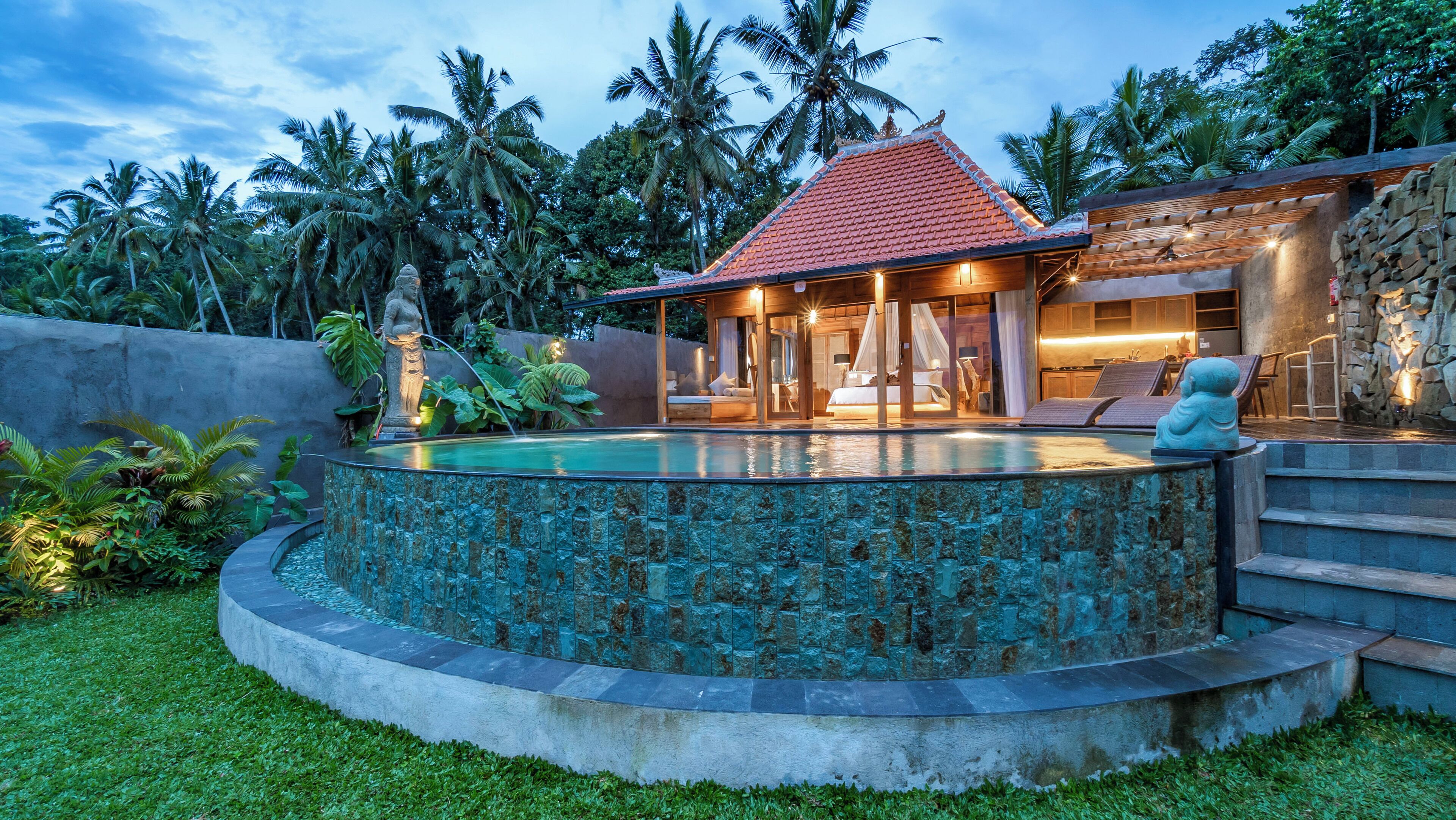 Ein tropisches Resort mit Swimmingpool, Steinmauer und Holzterrasse.
