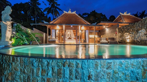A resort with a swimming pool, a covered outdoor area, and a stone wall. - Aix di Sawah Ubud (Tegallalang)