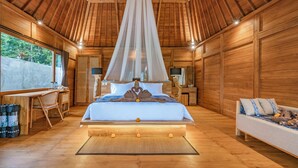 A wooden cabin bedroom with a bed, bedside table, and a window. - Aix di Sawah Ubud (Tegallalang)