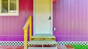 A white door with a green handle, a wooden bench, and a white picket fence. - Near Dtwn & Space Center: Tiny Home in Picayune (Picayune)