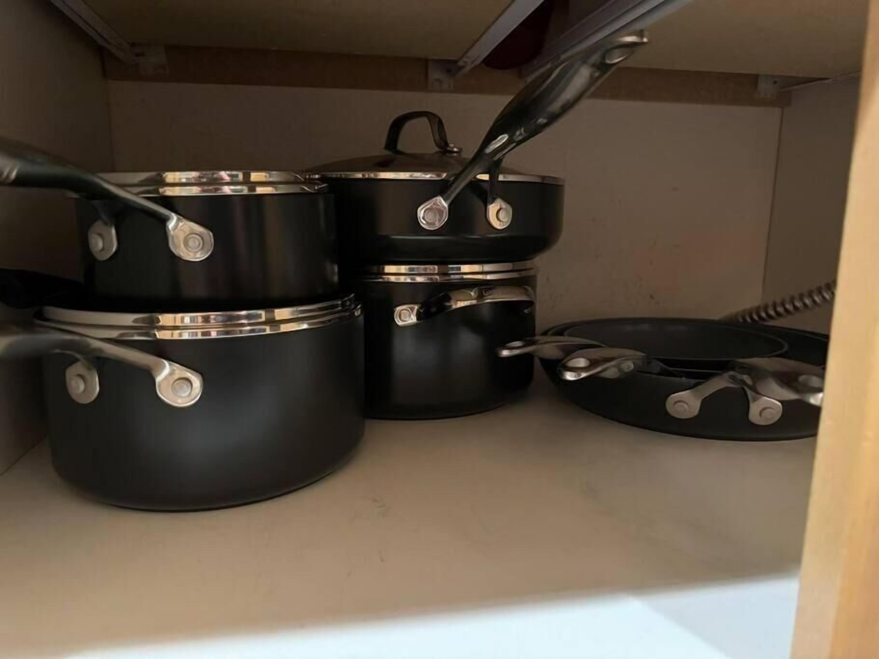 A kitchen with black pots and pans on a countertop.
