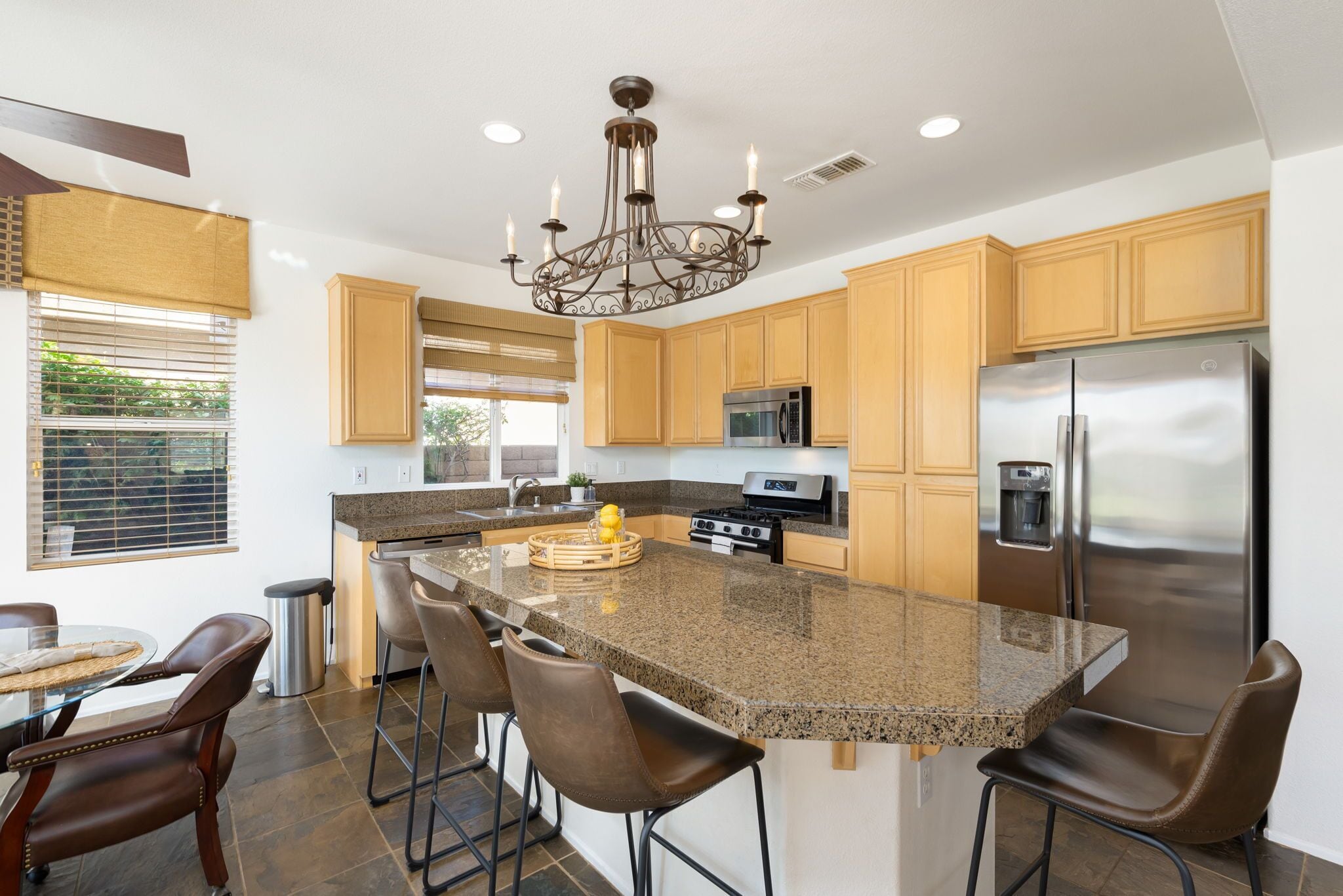 A modern kitchen with granite countertops, stainless steel appliances, and a central island with bar stools.