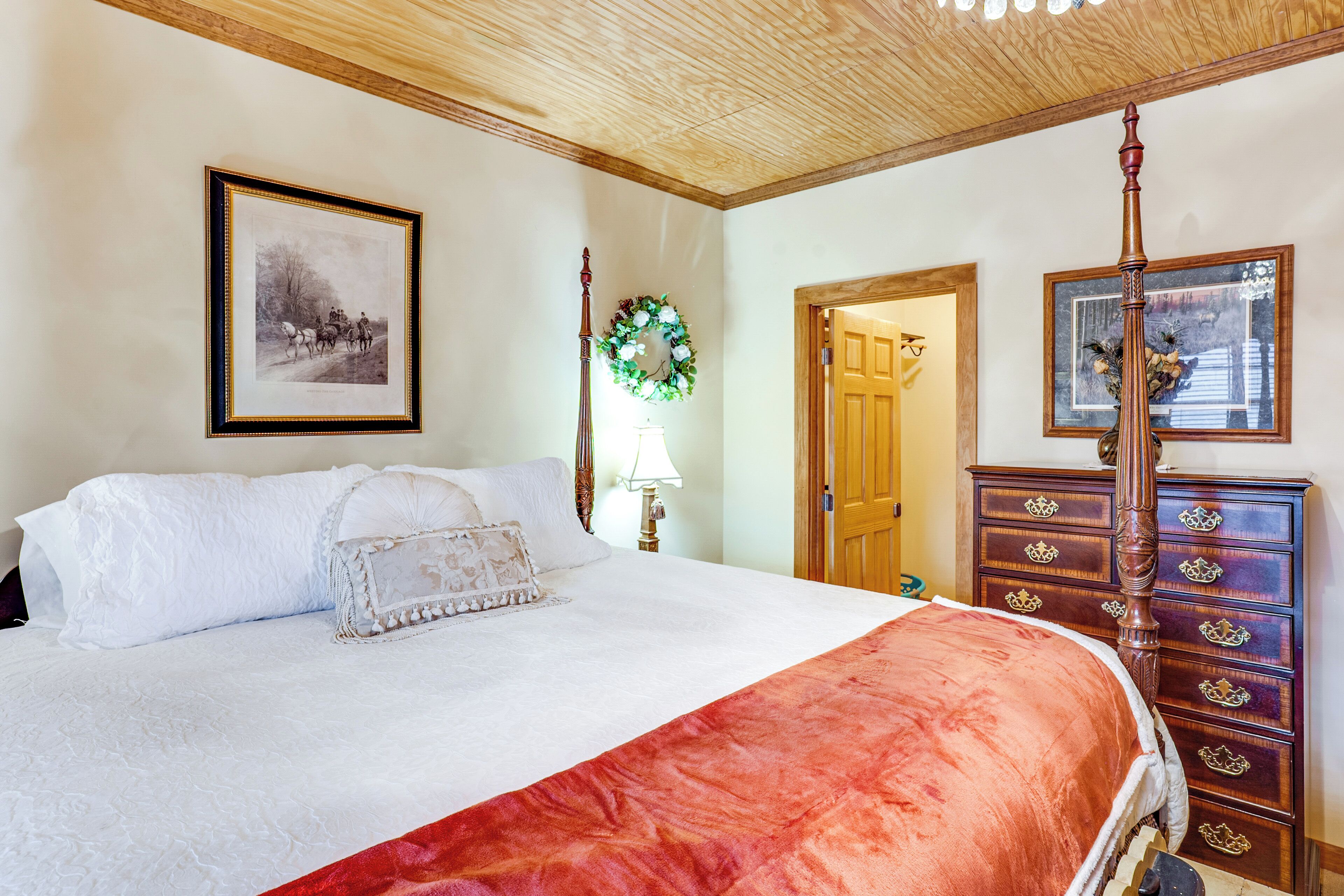 A bedroom with a four-poster bed, a wooden dresser, and a framed picture on the wall.
