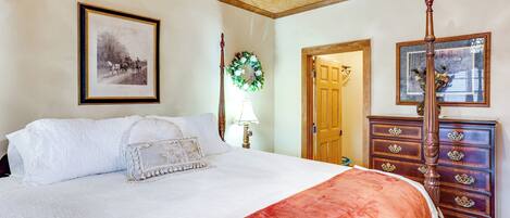 A bedroom with a four-poster bed, a wooden dresser, and a framed picture on the wall.
