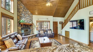A spacious living room with a stone fireplace, leather sofas, and a large TV. - Golf, Hike, Explore! Family-Friendly Pinetop Haven (Pinetop Country Club)