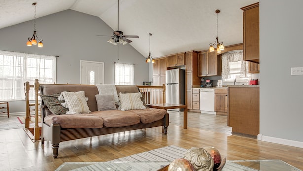 A spacious living room with a large sofa, wooden flooring, and a dining area with a kitchen in the background. - Near Tennessee River! Pet-Friendly Family Cottage! (Savannah)