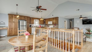 A spacious kitchen with wooden cabinets, a stainless steel refrigerator, and a dining area with a wooden table and chairs. - Near Tennessee River! Pet-Friendly Family Cottage! (Savannah)