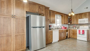 A kitchen with wooden cabinets, stainless steel appliances, and a tiled floor. - Near Tennessee River! Pet-Friendly Family Cottage! (Savannah)