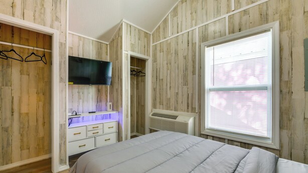 Een slaapkamer met een bed, een tv aan de muur, een kledingkast en een raam met zonwering.