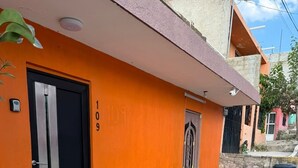 En byggnad med en orange fasad, en svart dörr och ett litet fönster.