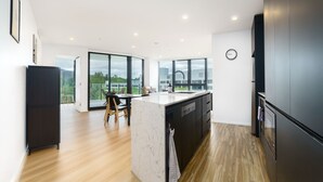 Een moderne keuken met een marmeren eiland, zwarte kastjes en een groot raam met uitzicht op groen.