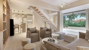 Een moderne woonkamer met een trap, een keuken en uitzicht op de omgeving.