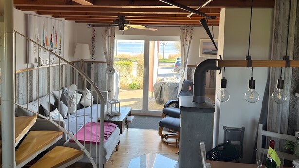 Un ambiente acogedor con una escalera, una cama, una mesa y vistas a través de una puerta.