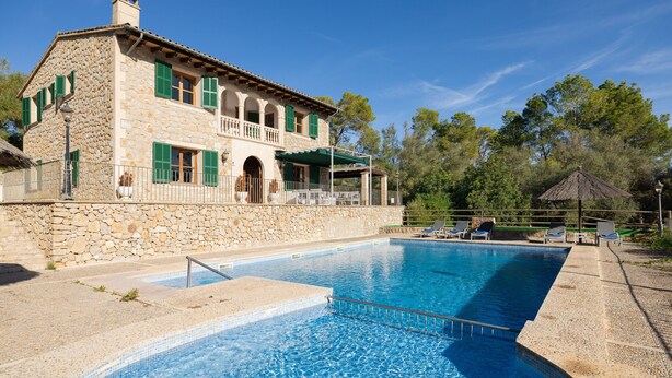 Un bâtiment en pierre doté d’une piscine, d’un espace extérieur aménagé pour s’asseoir et d’un patio couvert.