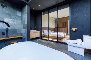 A modern bathroom with a large bathtub, a shower, and a toilet. - Himawari House (Blahbatuh)