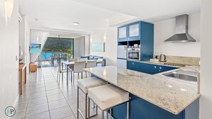 Una cocina moderna con armarios azules, encimera de granito y electrodomésticos de acero inoxidable.
