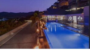 Un hotel moderno con piscina, mobiliario exterior y vistas a las montañas.