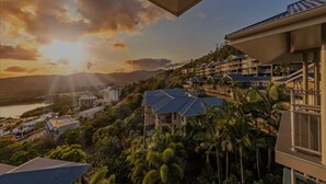 Un resort con varias edificaciones, vista al océano y palmeras.