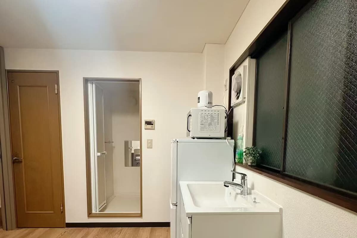 A compact kitchen with a white sink, a microwave, and a small trash bin.