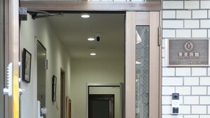 A hotel entrance with a tiled floor, a door with a glass panel, and a signboard above the door. - AOMUGI RYOKAN (Tokyo)