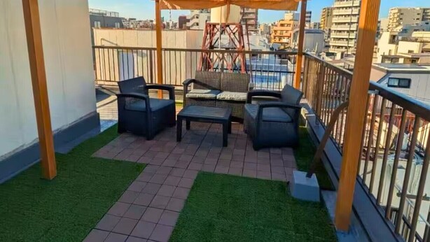 A rooftop terrace with a pergola, two chairs, a table, and a view of the cityscape. - AOMUGI RYOKAN (Tokyo)