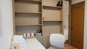 A hotel room with a wooden desk, a chair, a bed, and built-in shelving with a few items on it. - AOMUGI RYOKAN (Tokyo)