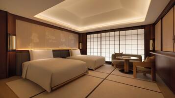 A hotel room with a large bed, a sofa, a small table, and a view through a large window.