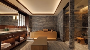 A modern bathroom with a wooden vanity, a bathtub, and a marble wall. - Capella Kyoto (Kyoto)
